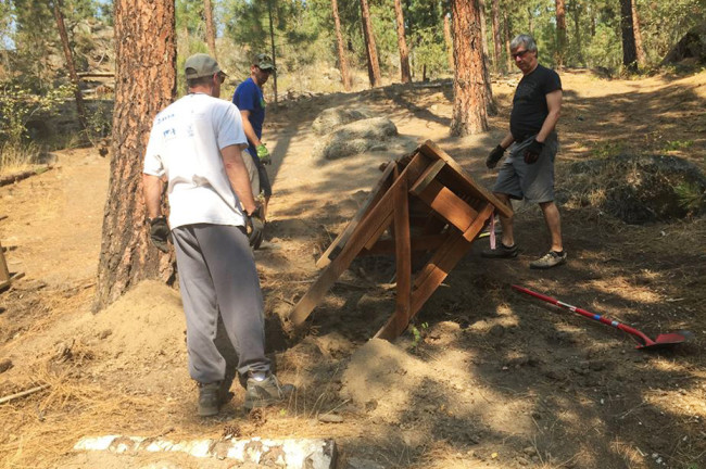 Volunteers remove an old mountain bike feature at Camp Sekani, Spokane.
