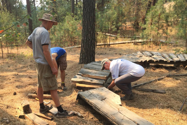 Volunteers make repairs to a mountain bike feature in the skills park at Camp Sekani, Spokane.